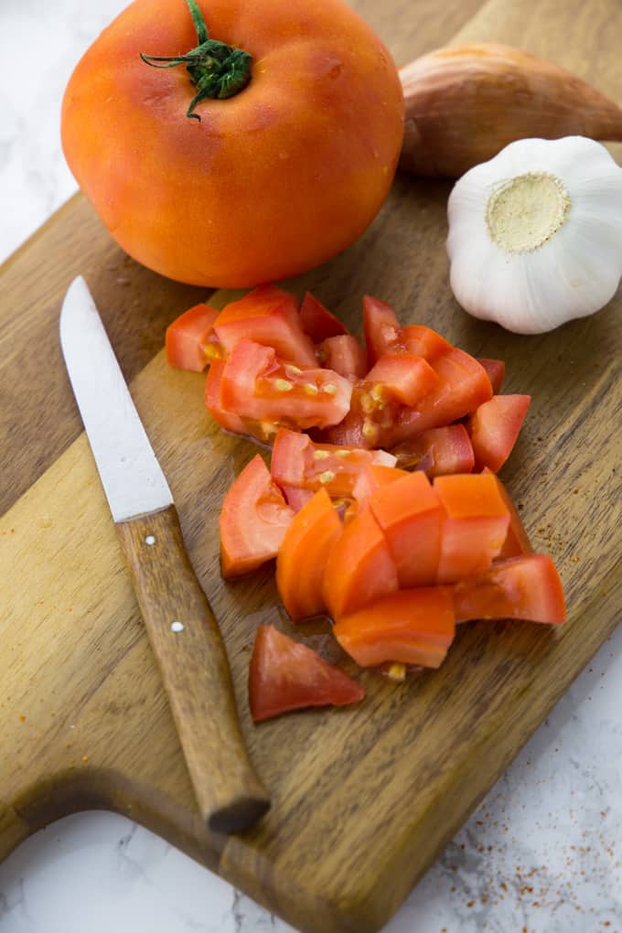 Gewürfelte Tomaten mit einem Messer auf einem Holz-Schneidebrett