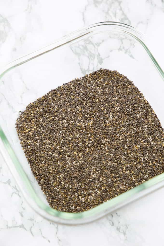 Chia Samen in einer viereckigen Glasschüssel auf einer Marmorplatte 