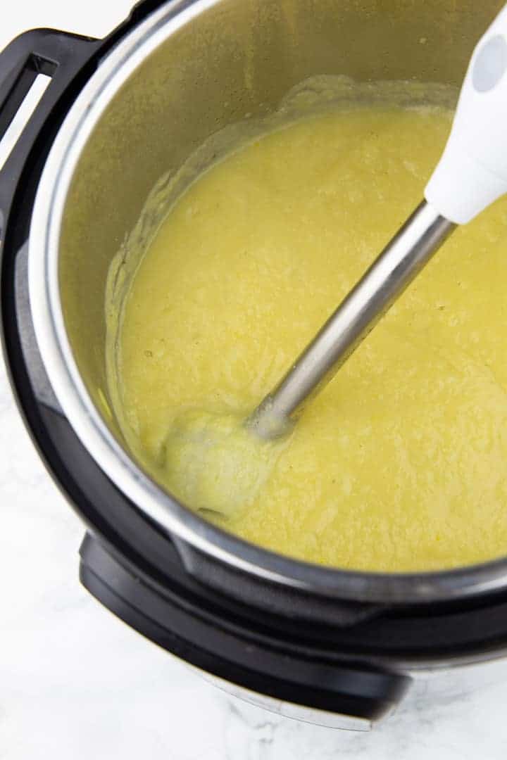 Cremige Suppe mit Blumenkohl und Kartoffeln im Instant Pot auf einer Marmorplatte mit einem Pürierstab