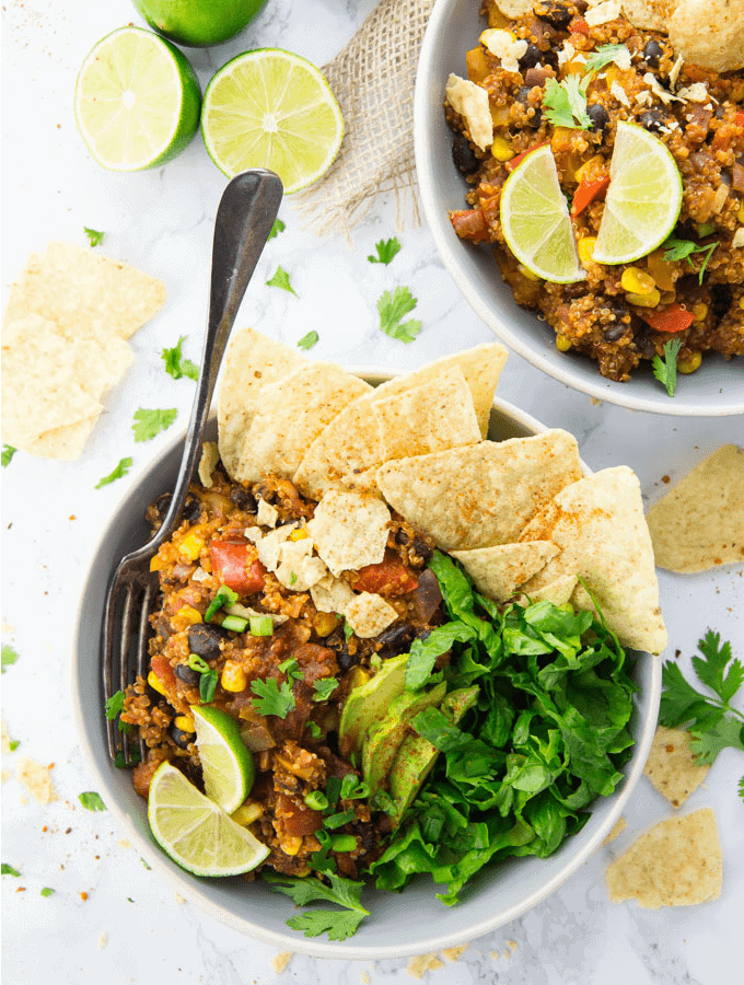 zwei Taco Bowls mit Quinoa, Salat und Nacho Chips auf einer Marmorplatte