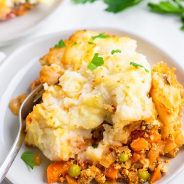 Nahaufnahme von einer Shepherd's Pie auf einem weißen Teller mit einer Gabel