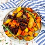 ein Teller mit Ofengemüse und einer Gabel auf einem Holzbrett