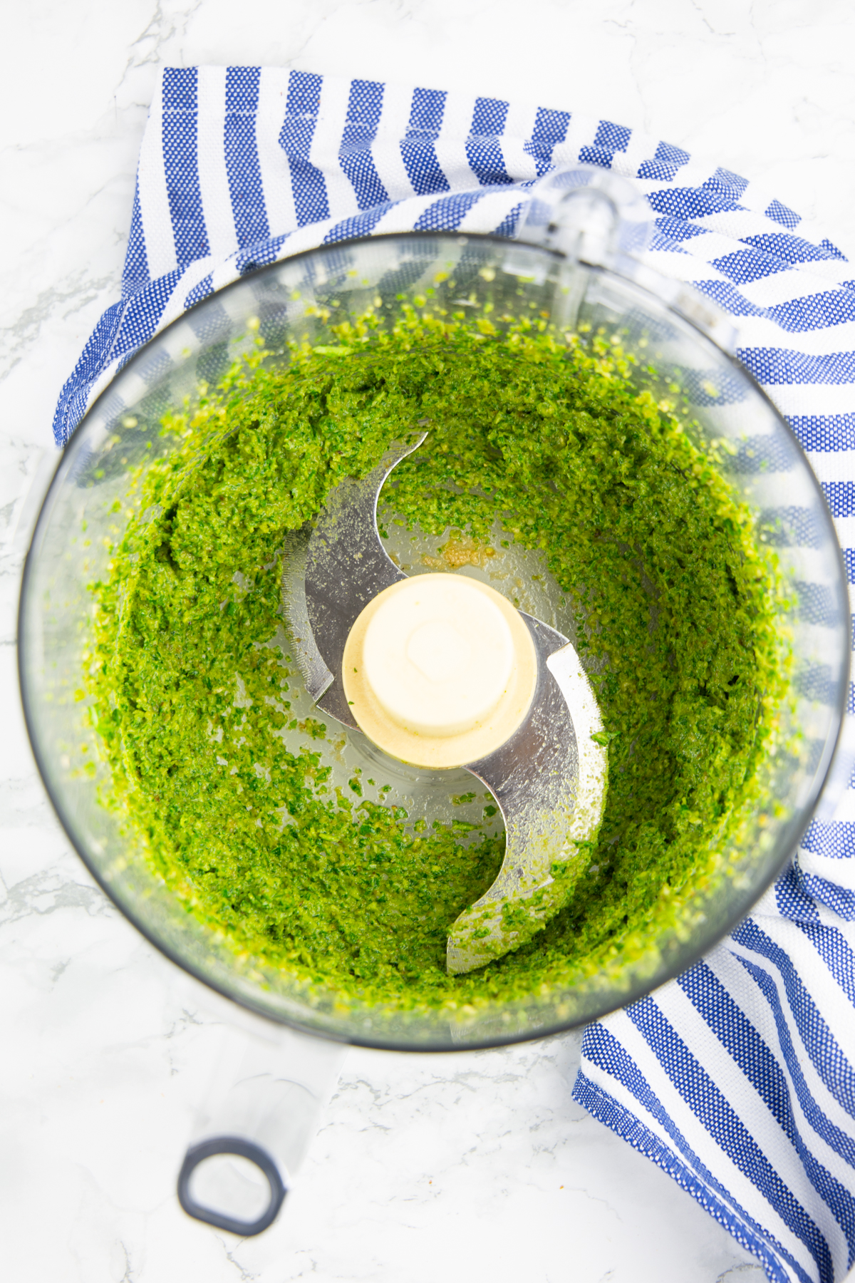 grünes Pesto in einer Küchenmaschine auf einer Marmorplatte 