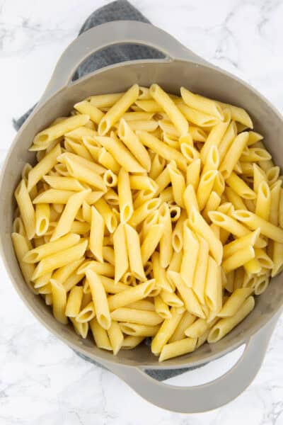 gekochte Penne in einem grauen Sieb auf einer Marmorplatte