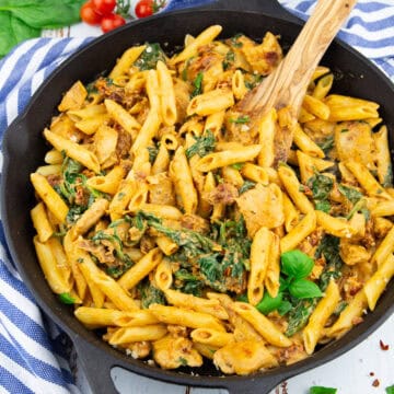 eine gusseiserne Pfanne mit Penne mit getrockneten Tomaten und Spinat