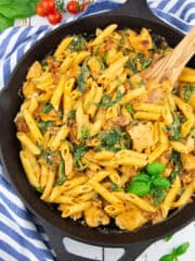 eine gusseiserne Pfanne mit Penne mit getrockneten Tomaten und Spinat