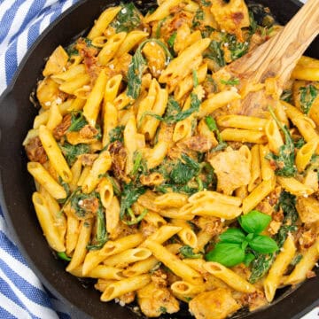 eine gusseiserne Pfanne mit Penne mit getrockneten Tomaten und Spinat