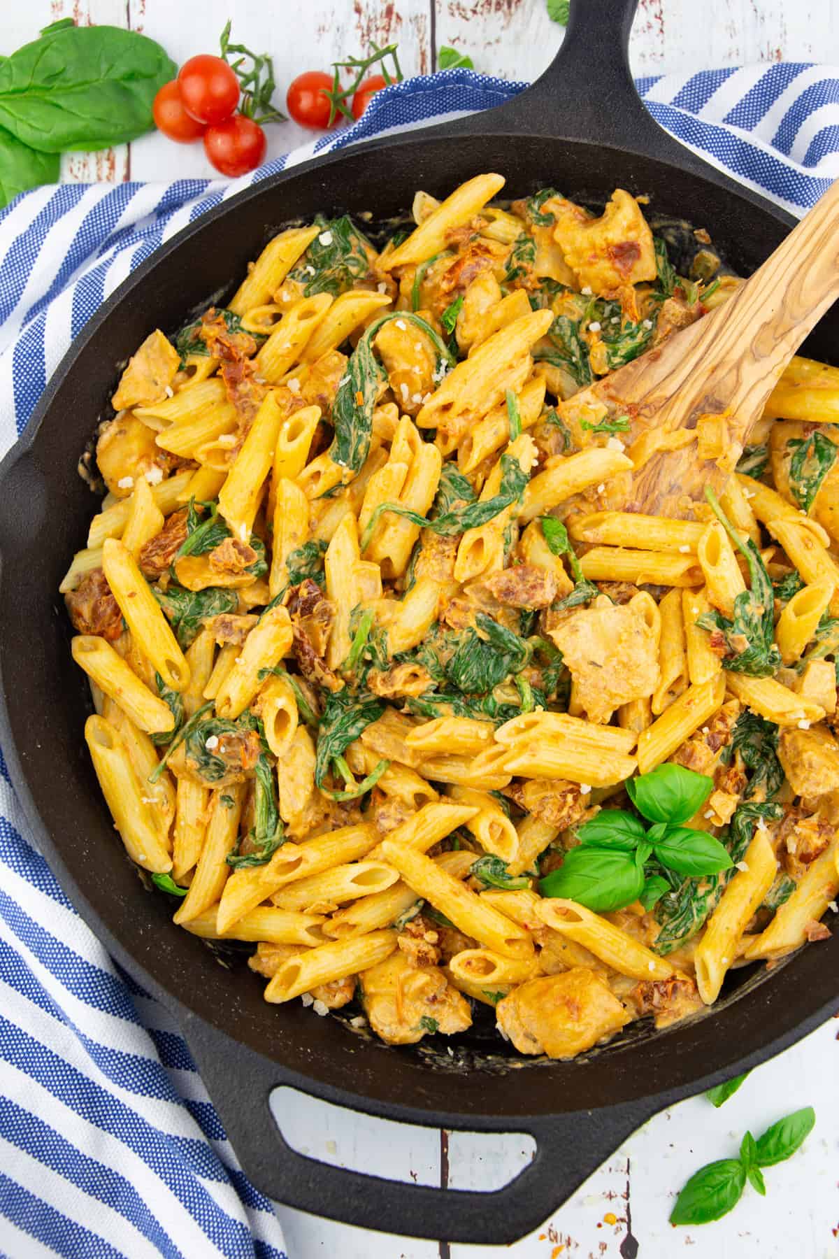 eine gusseiserne Pfanne mit Penne mit getrockneten Tomaten und Spinat