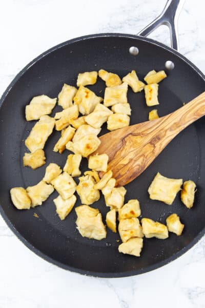 vegane Hähnchenstücke in einer schwarzen Pfanne mit einem Holzlöffel