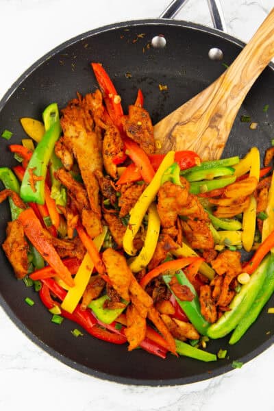 eine schwarze Pfanne mit angebratenen Paprikastreifen sowie Veganer Hähnchen