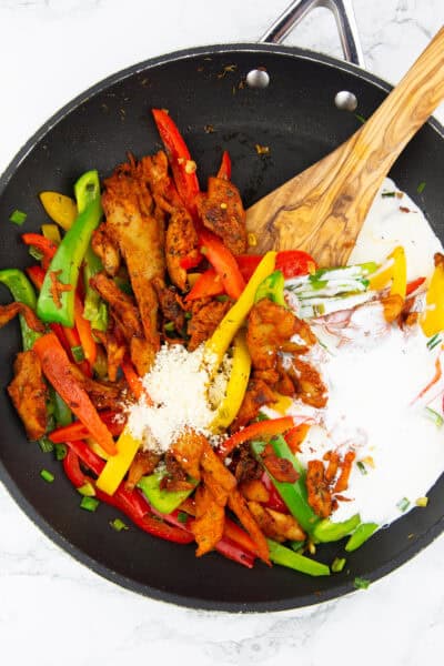 eine schwarze Pfanne mit angebratenen Paprikastreifen und Veganer Hähnchen mit Sojasahne