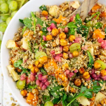 eine weiße Schüssel mit Quinoa Salat mit Süßkartoffeln auf einem weißen Holzbrett