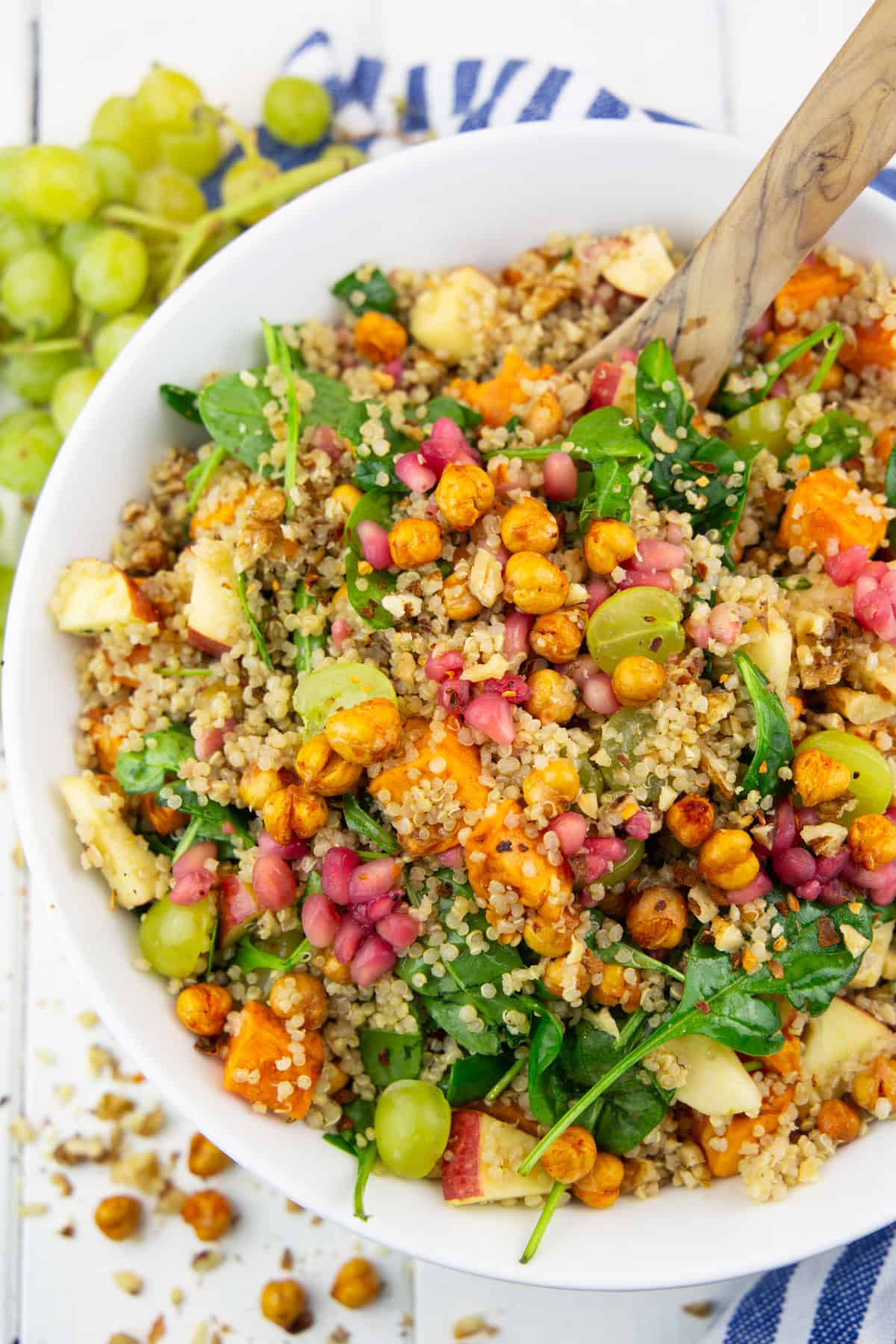 eine weiße Schüssel mit Quinoa Salat mit Süßkartoffeln auf einem weißen Holzbrett 
